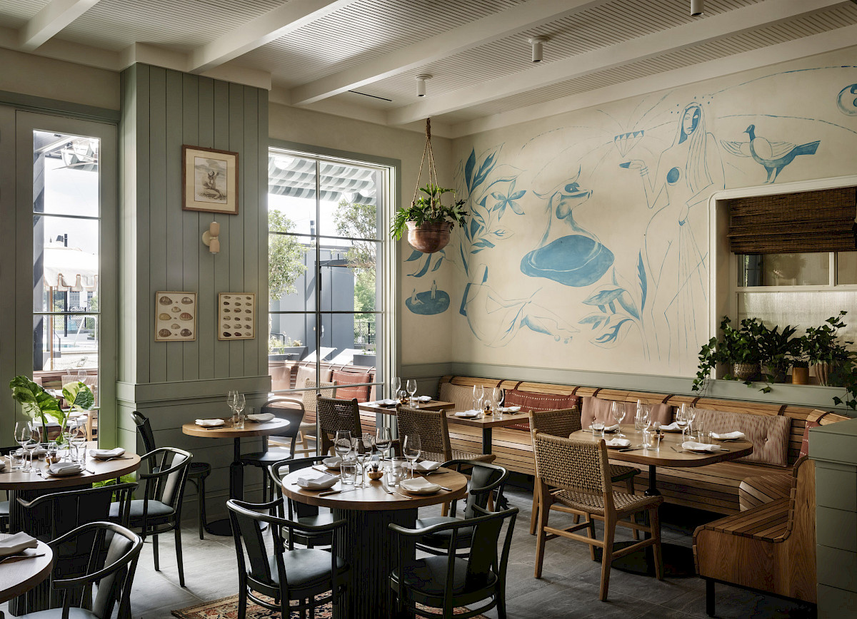 Elektra’s dining room with a blue mural, rattan chairs and leather banquettes