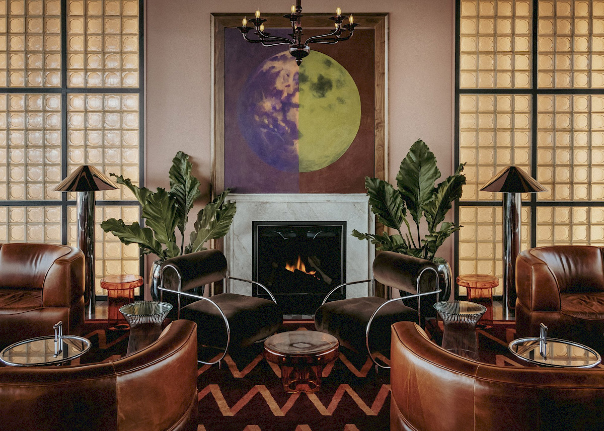 Moonlight’s lounge with leather armchairs gathered around the fireplace beneath a moon painting